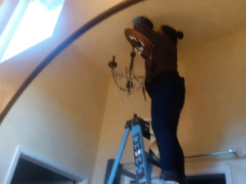 Electrician installing a chandelier in a Johnson Creek residence